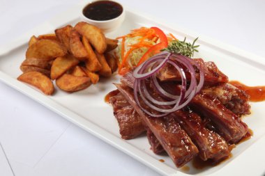 Soslu domuz kaburgası ve tabakta biberiye.