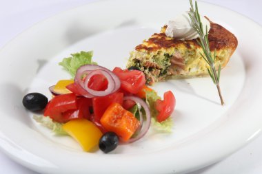 Beyaz tabakta sebzeli balık turtası.