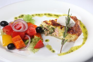 Beyaz tabakta sebzeli balık turtası.