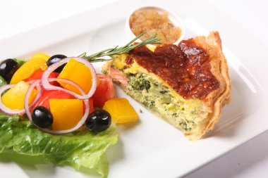 Beyaz tabakta sebzeli balık turtası.