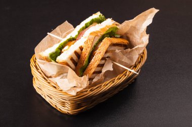 siyah bir zemin üzerine bir sepet içinde sandviç