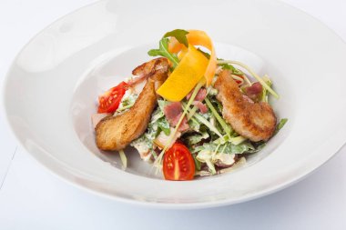 Beyaz tabakta pike soslu salata.