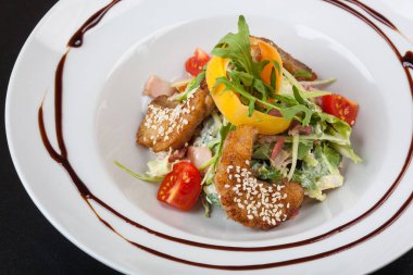 Beyaz tabakta pike soslu salata.