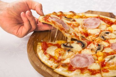Beyaz arka planda bir dilim pizzayı tutan el.