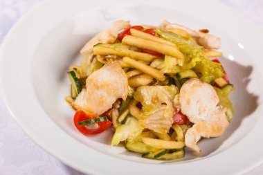 Beyaz tabakta tavuk göğsü olan salata.