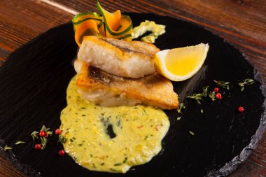 Siyah tabakta limon ve soslu turna levreği.