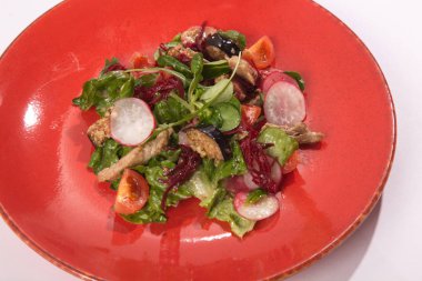 Beyaz arka planda kırmızı tabakta turplu salata.