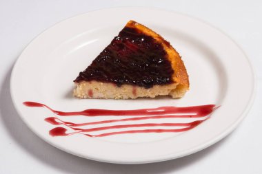 Siyah üzümlü cheesecake ve beyaz tabakta yaban mersini sosu.