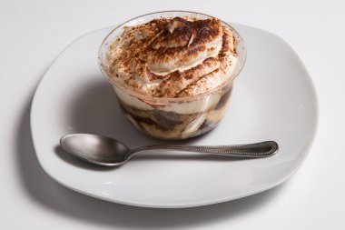 Beyaz masada izole edilmiş bir bardak tiramisu.