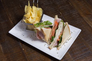 Beyaz tabakta jambonlu ve cipsli lezzetli sandviç.