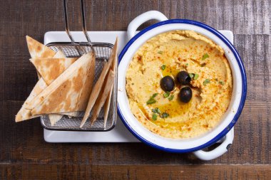 Bir kase kremalı civciv bezelye humusu, zeytinyağı ve pide cipsi..