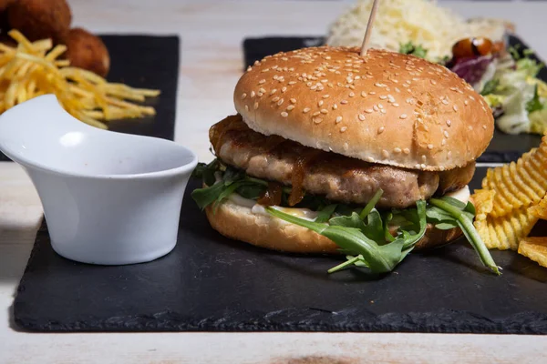 Shot of burger with chips and tomato sauce.