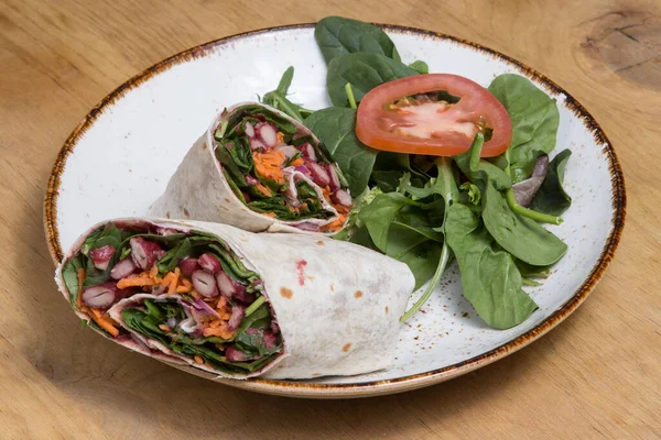 Vegan wrap with salad on a white plate