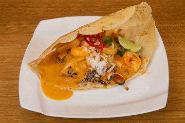 Beyaz tabakta deniz ürünleri mürekkep balığı, karides ve midye.