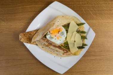 Beyaz tabakta peynirli, yumurtalı ve kuşkonmaz.