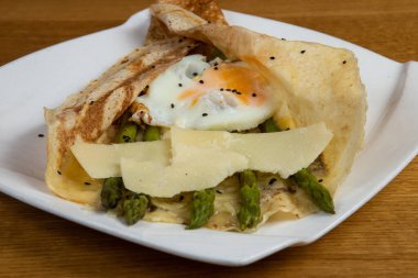 Beyaz tabakta peynirli, yumurtalı ve kuşkonmaz.