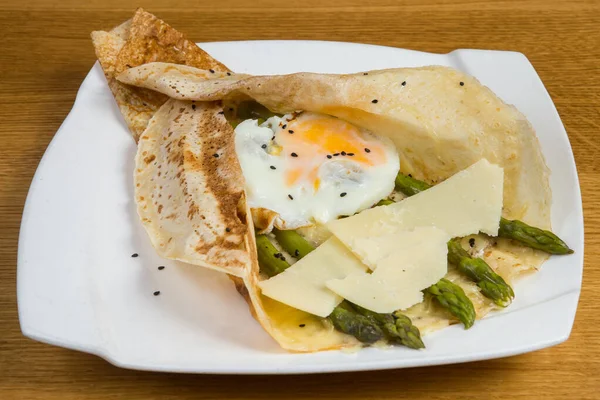 Beyaz tabakta peynirli, yumurtalı ve kuşkonmaz.