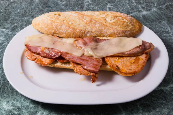 Tasty sandwich with chicken, ham and bacon served on white marble table