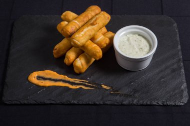 Tequenos adında, peynirle dolu kızarmış mısırdan yapılmış Latin Amerika mezeleri..