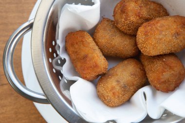 İspanyol kızartılmış altın sarısı patates kroketleri, yakın plan beyaz tabakta kroketler.