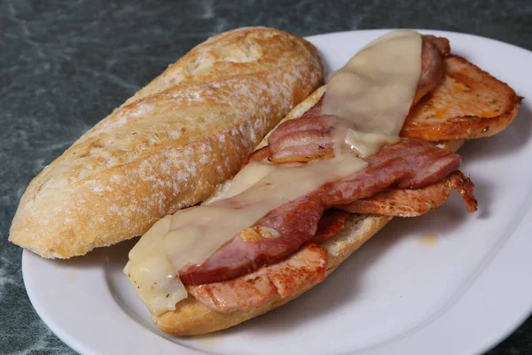 Tasty sandwich with chicken, ham and bacon served on white plate