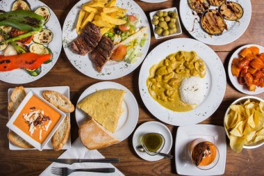 Yukarıdan çekilmiş bir sürü İspanyol tapas yemeğinin resmi, koyu kırsal bir arka planda.