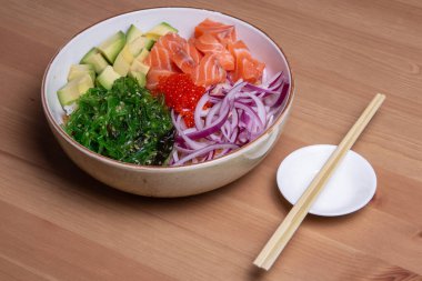 Avokado, salatalık, pirinç ve susam tohumlu Hawaii Somon Kabı tropikal yaprakların üzerinde servis edilir. Suşi kasesi. Organik ve sağlıklı yiyecekler. Taze deniz ürünleri tarifi