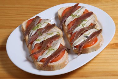 İspanyol bar yemekleri: Zeytin yağı, otlar, taze domatesler ve baharatlı ançüez filetoları ile ızgara ekmek dilimleri