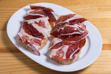 Doğal domatesli lezzetli ekmek tostu, ekstra saf zeytinyağı, İber jambonu.