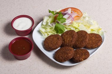 Falafel, nilüfer yaprağı beyaz bir tabakta salata ile dolu.