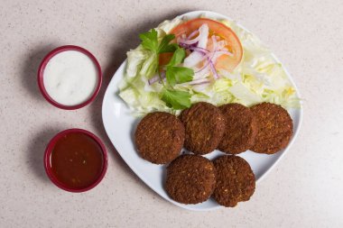 Falafel, nilüfer yaprağı beyaz bir tabakta salata ile dolu.