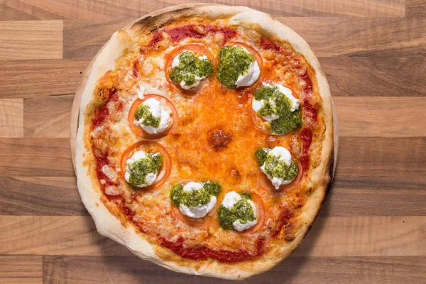 Pizza Margarita with pesto on wood background