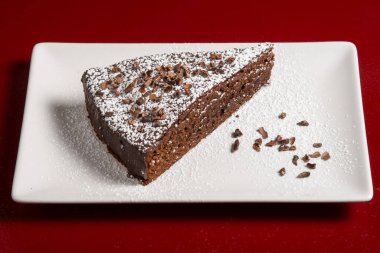 Beyaz arka planda kıvrımlı çikolatalı pasta dilimi.