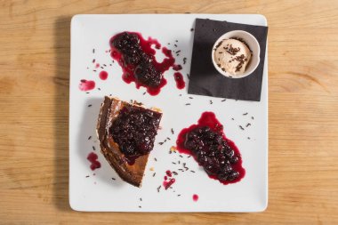 Ahududulu peynirli kek ve beyaz tabakta dondurma.