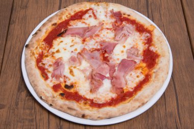 Beyaz tabakta peynirli ve jambonlu ev yapımı pizza