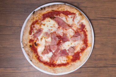 Beyaz tabakta peynirli ve jambonlu ev yapımı pizza