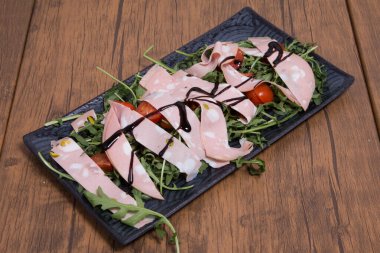 Arkaplanda roka, sosis ve domates salatası.