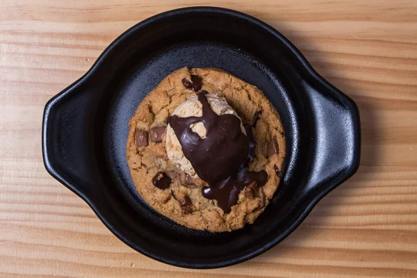 Chocolate chip cookies and ice cream on a black plate