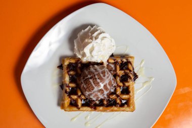 Ev yapımı kalın Belçika waffleları. Dondurma kepçesi ve kırmızı arka planda çikolata.