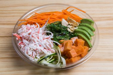 Şeffaf bir kasede avokado, havuç, papaya ve tavukla dürt.