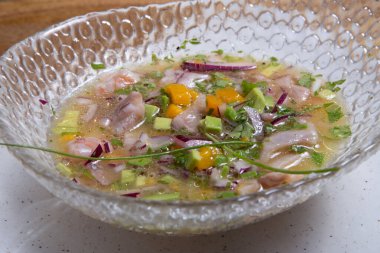 Yakın plan deniz levreği ceviche cam kase ahşap arka planda servis edilir. Taze ve lezzetli ceviche. Çiğ balık. Latin Amerika mutfağı.