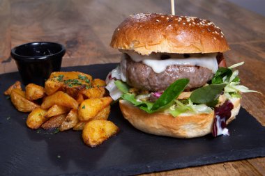 Siyah masada kızarmış patatesli leziz bir burger.