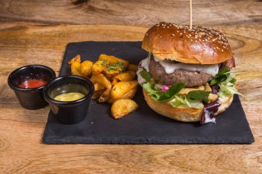 Siyah masada kızarmış patatesli leziz bir burger.