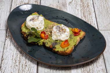 Ahşap bir arka planda avokado ve yumurta ile tost