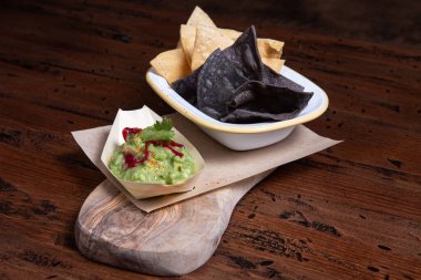 Salsa soslu mısır cipsi ve köy arka planında guacamole..