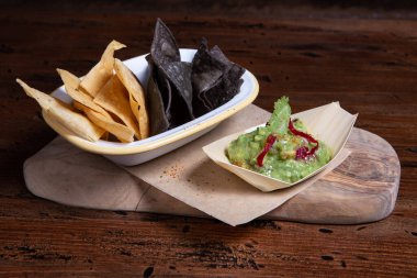 Salsa soslu mısır cipsi ve köy arka planında guacamole..