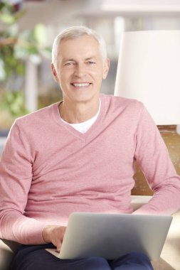 Dizüstü bilgisayar kullanan kıdemli adam.