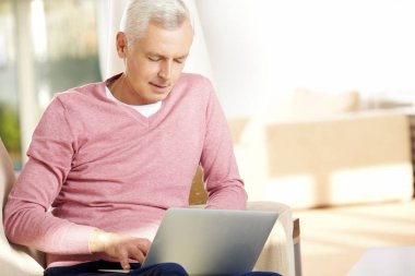 Dizüstü bilgisayar kullanan kıdemli adam.