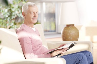 Son sınıf öğrencisi evde kitap okuyor.