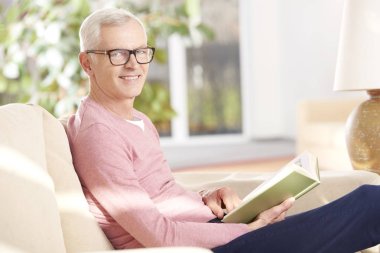 Kanepede kitap okuyan adam.